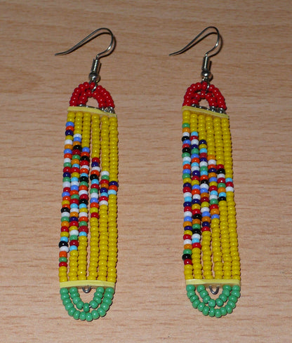 Longues boucles d'oreilles africaines multi-rangs composées de perles de rocaille jaunes, rouges, vertes et multicolores montées sur six rangées de fils de fer en forme de rectangles aux extrémités arrondies. 

Ces boucles d'oreilles à la mode kenyane et aux accents exotiques mesurent 9 cm de long et 1.5 cm de large ; elles se portent avec des crochets en acier inoxydable sur des oreilles percées.