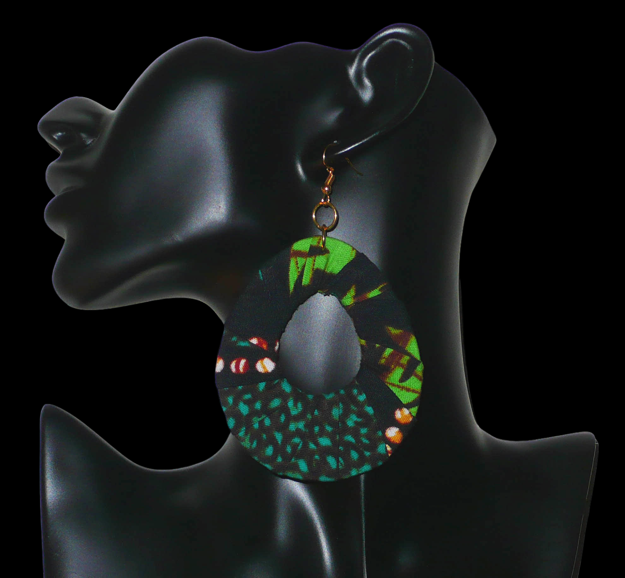 Boucles d'oreilles africaines surdimensionnées composées de bandes de tissu africain principalement vert et noir enroulées sur une structure en forme de gouttes. Elles mesurent 10,5 cm de long et 6,5 cm de large et se portent avec des crochets en acier inoxydable sur des oreilles percées. Timeless Fineries