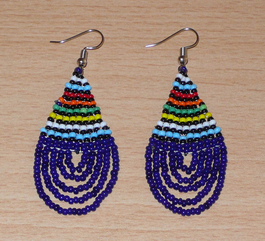 Boucles d'oreilles africaines zouloues en perles de rocaille bleu foncé et multicolores montées en forme de gouttes. Elles mesurent 7 cm de long et 2,5 cm de large, et se portent sur des oreilles percées.