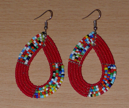 Boucles d'oreilles kenyanes multi-rangs en forme de gouttes composées de perles de verre rouges et multicolores enfilées sur plusieurs rangées de fils de fer.  Ces boucles d'oreilles aux accents bohème mesurent 8 cm de long et 4 cm de large, et se portent avec crochets en acier inoxydable sur des oreilles percées.