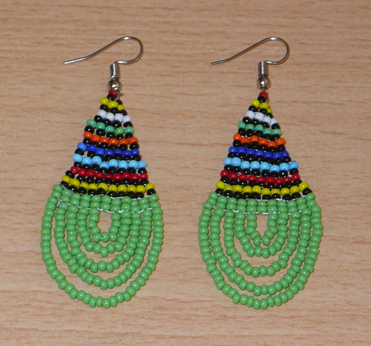 Boucles d'oreilles africaines de tradition zouloue en forme de gouttes composées d'un tissage de perles de rocaille vertes et multicolores. Elles mesurent 7 cm de long et 2,5 cm de large et se portent sur des oreilles percées. Timeless Fineries