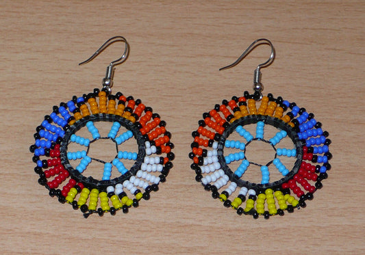 Boucles d'oreilles ethniques rondes à motifs zoulous composées de perles de rocaille bleu ciel et multicolores. De taille moyenne et légères à porter, elles mesurent 6 cm de long et 4 cm de large. Elles se portent avec des crochets en acier inoxydable sur des oreilles percées.