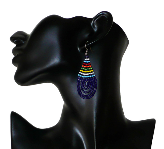 Boucles d'oreilles ethniques sud-africaines en forme de gouttes composées d'un tissage de perles de rocaille bleu foncé et multicolores. Elles mesurent 7 cm de long et 2,5 cm de large et se portent sur des oreilles percées. Photographiées sur un mannequin. Timeless Fineries