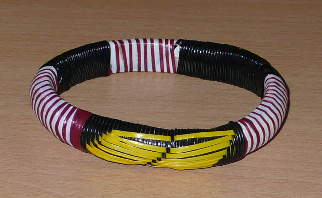 Bracelet africain eco-friendly à motifs ethniques tressés à partir de bandes de plastique recyclé noir, jaune, bordeaux et blanc.