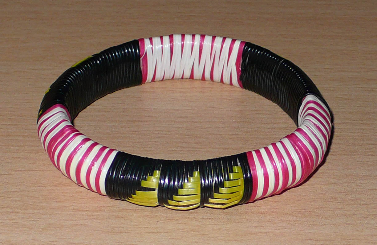 Bracelet africain eco-friendly fabriqué au Mali : il se compose de motifs ethniques tressés à partir de fines bandes de plastique recyclé noir, jaune, rose et blanc.

Ce bracelet a une circonférence de 19.5 cm, un diamètre de 6 cm et une épaisseur de 1.5 cm.