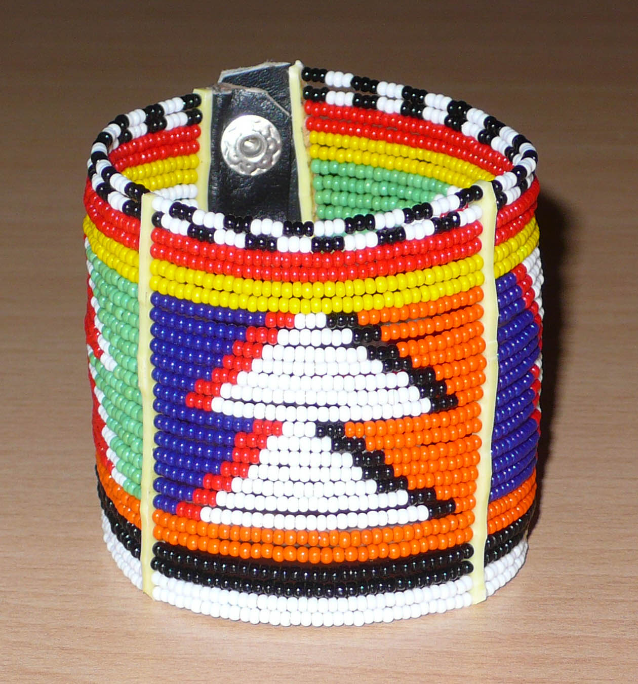 Bracelet africain traditionnel composé de 26 rangées de perles multicolores aux couleurs et motifs Massai glissées sur des fils de fer fixés sur des charnières en plastique.