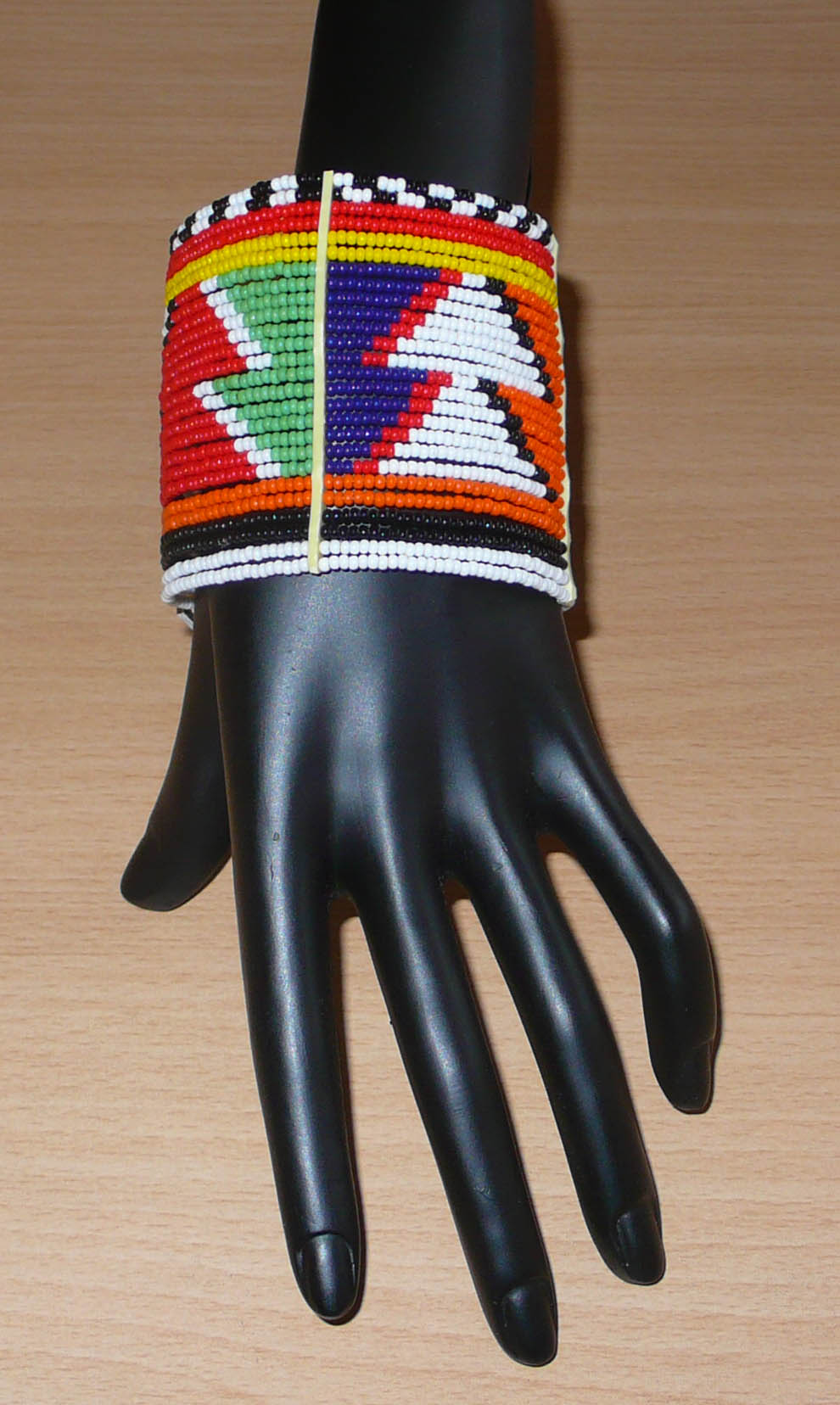 Bracelet africain traditionnel composé de 26 rangées de perles multicolores aux couleurs et motifs Massai glissées sur des fils de fer fixés sur des charnières en plastique.