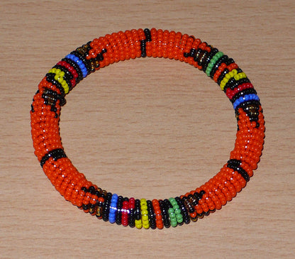 Bracelet africain traditionnel à motifs ethniques zoulous en perles de rocaille orange et multicolores enfilées sur du fil de nylon enroulé autour d'un tube en plastique.
La circonférence interne de ce bracelet est de 21 cm, son diamètre interne de 6.5 cm, et son épaisseur de 1 cm.
Bracelet unisexe pouvant être porté par une femme ou par un homme.