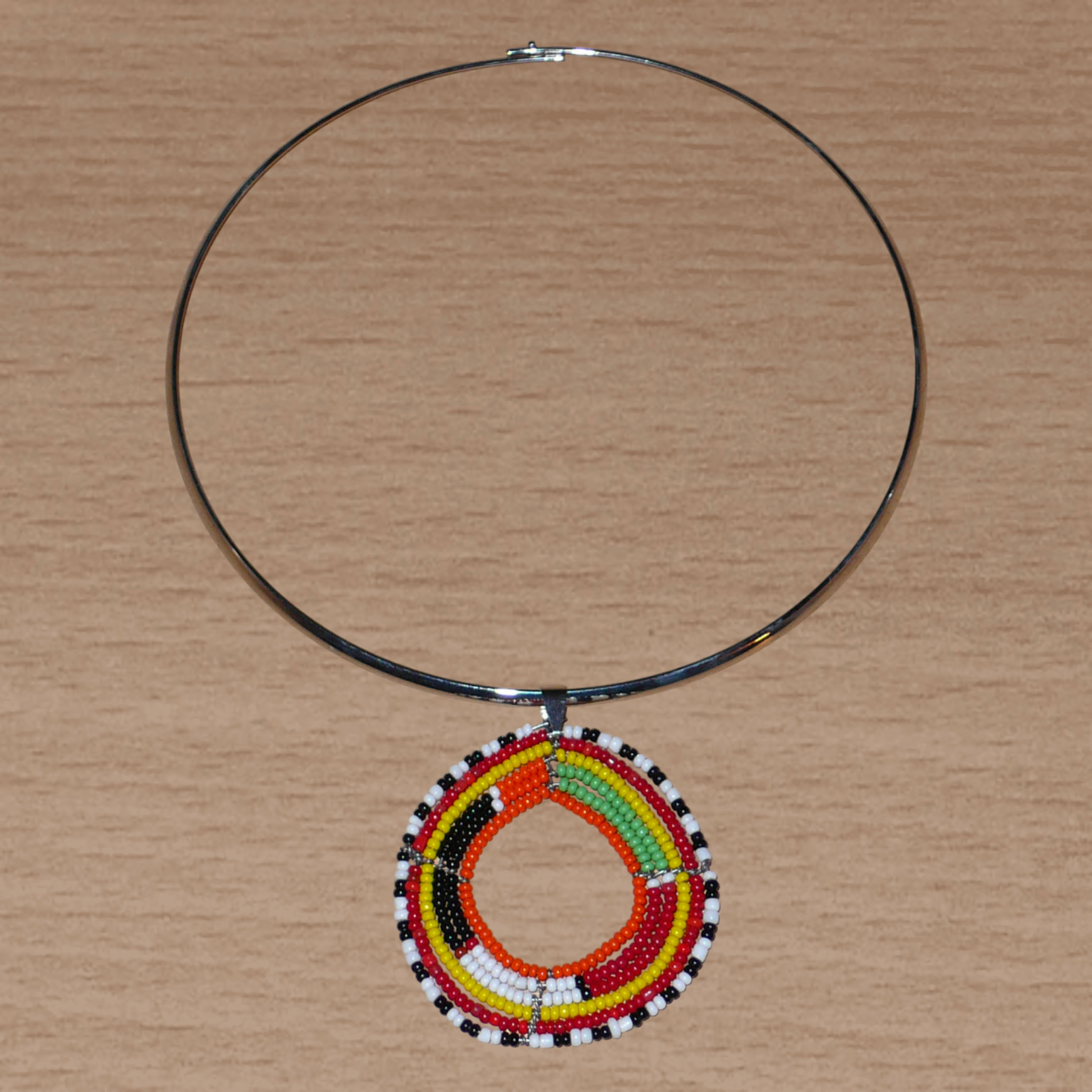 Collier ras de cou africain en laiton orné d'un médaillon Massai fait de perles de rocaille multicolores.