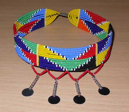 Collier ras de cou africain Massai composé de douze rangées de perles de rocaille multicolores enfilées sur des fils de fer insérés dans des charnières en plastique jaune. Le collier est décoré chaînettes prolongées de petits disques métalliques ; il se ferme avec un crochet.