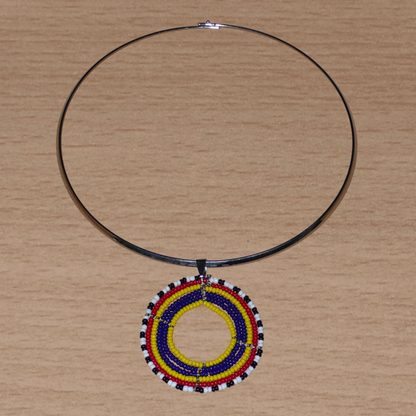 Collier ethnique aux accents afro bohème composé d'un ras de cou en laiton orné d'un médaillon Massai fait de perles de rocaille bleu foncé, jaunes, rouges, blanches et noires.