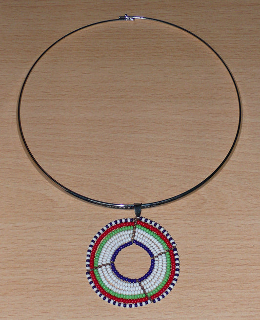 Collier ethnique contemporain composé d'un ras de cou en laiton orné d'un médaillon Massai fait de perles de rocaille blanches, vertes, rouges, bleu marine et noires glissées sur sept rangées de fils de fer montés en cercles.