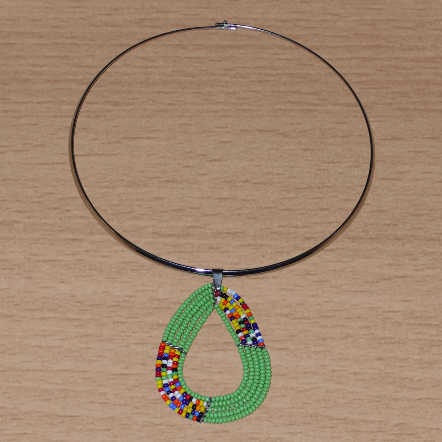 Collier ethnique vert et multicolore composé d'un ras de cou en laiton agrémenté d'un pendentif kenyan triangulaire aux bords arrondis fait de  perles de rocaille.