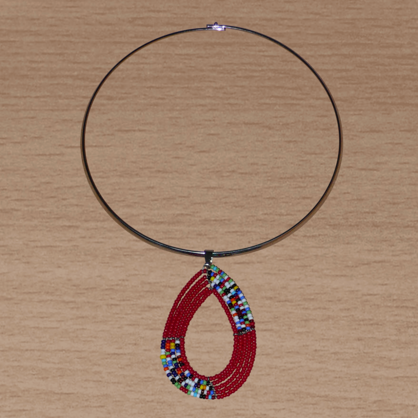 Collier ethnique rouge et multicolore composé d'un ras de cou en laiton orné d'un long pendentif en forme de goutte fait de perles de rocaille.