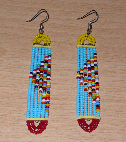 Longues boucles d'oreilles africaines à la mode kenyane composées de perles de rocaille bleu ciel, rouges, jaunes et multicolores montées sur six rangées de fils de fer en forme de rectangles aux extrémités arrondies. 

Ces boucles d'oreilles aux accents exotiques mesurent 9 cm de long et 1.5 cm de large ; elles se portent avec des crochets en acier inoxydable sur des oreilles percées.