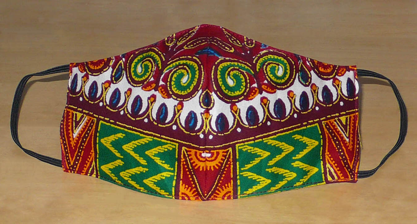 Masque textile ajusté, coupé et cousu dans un tissu africain en coton imprimé de motifs ethniques multicolores ; il se porte avec des élastiques. Fabriqué dans une démarche éco-responsable, ce masque est lavable et réutilisable.