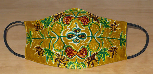 Masque facial textile à la coupe ajustée, cousu dans un beau tissu en coton à motifs africains ; il se porte avec des élastiques. En vue d'une utilisation eco-friendly, ce masque est lavable et réutilisable.  Ce masque aux accents afro-caribéens mesure 21 cm de long, et 40 cm en comptant les élastiques ; il a une hauteur de 12 cm (du haut du nez jusqu'au menton) et une largeur sur les côtés de 7 cm.