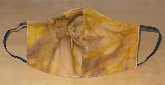 Masque facial textile à la coupe ajustée, cousu dans un tissu en coton imprimé Tie and Dye aux nuances de couleurs marron, beige et jaune ; il se porte avec des élastiques. En vue d'une utilisation eco-friendly, il est lavable et réutilisable.