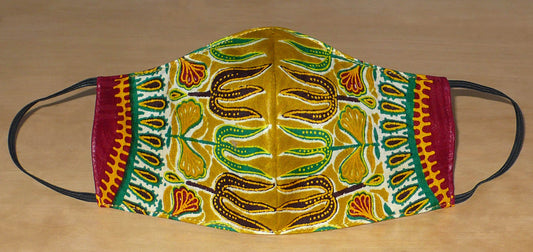 Beau masque facial en tissu africain couleur moutarde imprimé de motifs ethniques multicolores ; il se porte avec des élastiques. Pour un usage éco-responsable, il est lavable et réutilisable.  Ce masque textile aux accents exotiques mesure 21 cm de long, et 40 cm en comptant les élastiques ; il a une hauteur de 12 cm (du haut du nez jusqu'au menton) et une largeur sur les côtés de 7 cm.