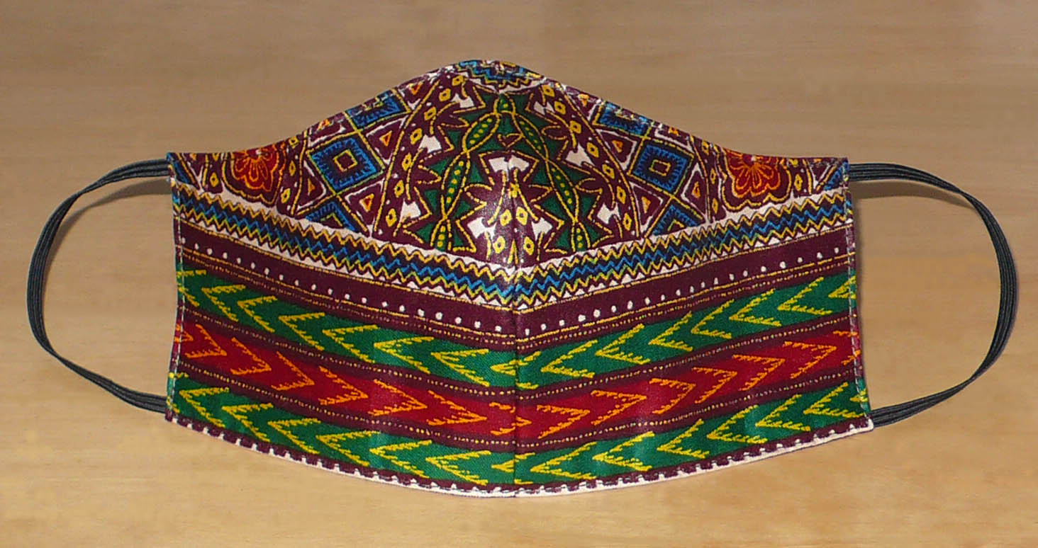 Masque facial au style ethnique, coupé et cousu dans un tissu en coton à motifs africains. Lavable et réutilisable, il se porte avec des élastiques.