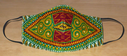 Masque facial textile à la coupe ajustée, cousu dans un superbe tissu africain en coton à motifs tribaux ; il se porte avec des élastiques. En vue d'une utilisation eco-friendly, ce masque est lavable et réutilisable.  Ce masque au style afro-caribéen mesure 21 cm de long, et 40 cm en comptant les élastiques ; il a une hauteur de 12 cm (du haut du nez jusqu'au menton) et une largeur sur les côtés de 7 cm.